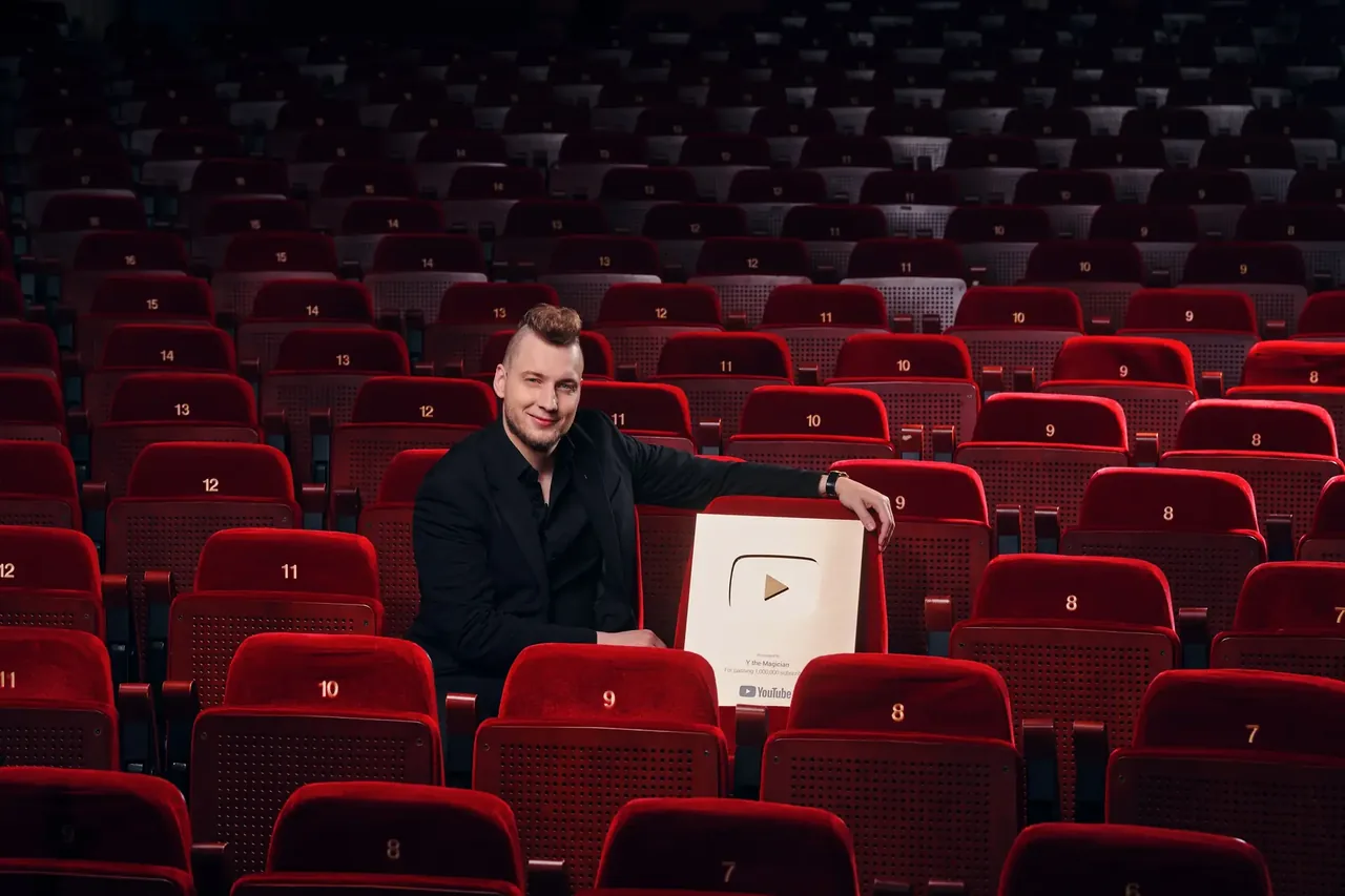 Iluzjonista Y wśród czerwonych foteli teatralnych ze złotą nagrodą YouTube